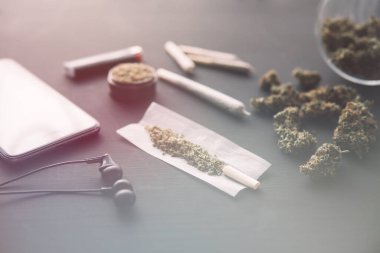 Esrarlı esrar, siyah masada marihuana tomurcukları, yakın çekim, elinde taze esrarla öğütücü, ışık renk tonları sızdırıyor