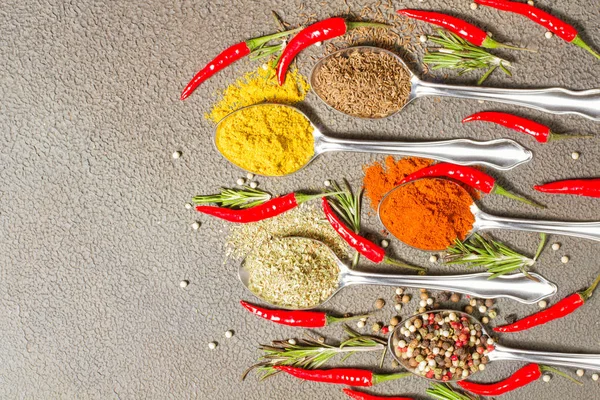 Gri arka plan üzerine bir kaşık içinde çeşitli baharatlar