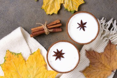 Sonbahar kuru yapraklı bir bardak eggnog. Sade beyaz eşarp. Üst görünüm