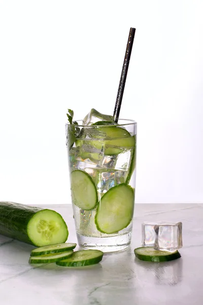 Glass of cucumber water with ice on white background.