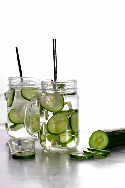 Glass of cucumber water with ice on white background.