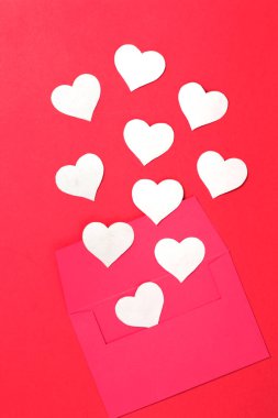 Kırmızı arkaplanda kalpler olan kırmızı bir zarf. Sevgililer Günü. Uzayı kopyala, maketle