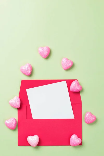 Червоний конверт на зеленому тлі з серцями. Валентинів день. Копіювальний простір, макет. — стокове фото