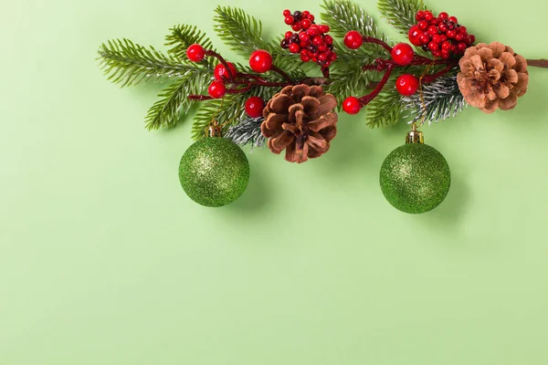 Yeşil arka planda konileri olan Noel köknar dalıyla Xmas oyuncakları. Uzayı kopyala, maketle 