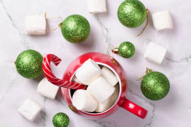 Noel içkisi. Sıcak çikolatalı kırmızı kupa ve mermer arka planda lokum. Noel baloları ve ladin dalları. Şeker kamışı. Üst görünüm