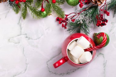 Noel içkisi. Sıcak çikolatalı kırmızı kupa ve mermer arka planda lokum. Noel baloları ve ladin dalları. Şeker kamışı. Üst görünüm