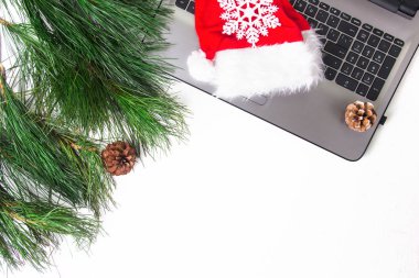 Ofis beyazı masa, bilgisayar, çam dalı ve Noel Baba şapkası. Noel arkaplanı. Boşluğu kopyala.