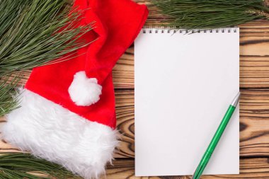 Noel arkaplanı boş defter, çam dalları, Noel Baba şapkası ve tahta masada Noel oyuncakları. Uzayı kopyala Düz yatıyordu