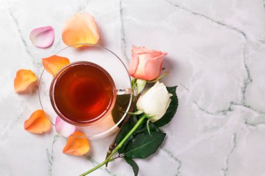 Mermer arka planda bir fincan sabah çayı ve gülleri