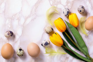 Tüylü ve laleli Paskalya yumurtaları sepette. Mermer arka planda. Üst görünüm.