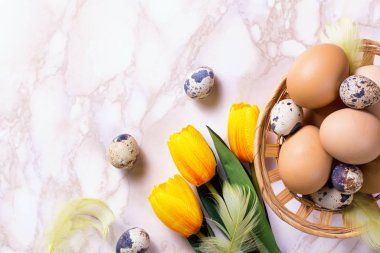 Tüylü ve laleli Paskalya yumurtaları sepette. Mermer arka planda. Üst görünüm.