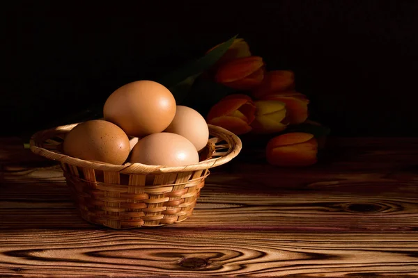 Easter eggs in basket with feather. On black background.Morning light.