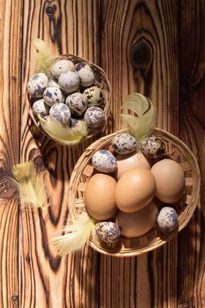 Ostereier im Korb mit Federn und Tulpen. auf einem hölzernen Hintergrund. Morgenlicht. rustikaler Stil. Ansicht von oben. — Stockfoto