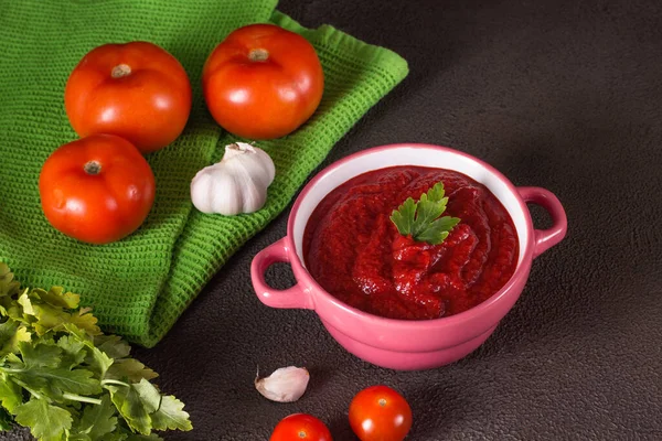 Zupa pomidorowa z pietruszką, cebulą i czosnkiem na szarym tle. Wygodne jedzenie. styl rustykalny — Zdjęcie stockowe
