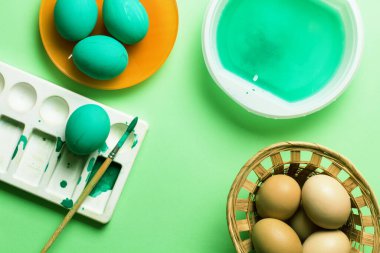 Colored easter eggs with feathers on a green background. Monochrome. Top view.