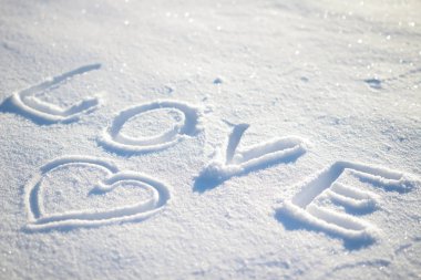 Kar ve kalp üzerinde yazılı kelime aşk