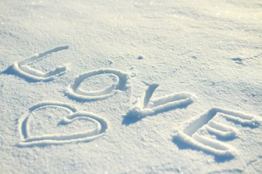 Kelime aşk ve karda çizilmiş bir kalp.