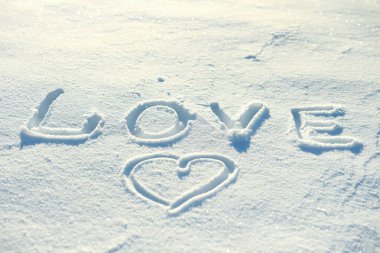 Kelime aşk ve karda çizilmiş bir kalp.