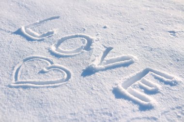 Kelime aşk ve karda çizilmiş bir kalp.