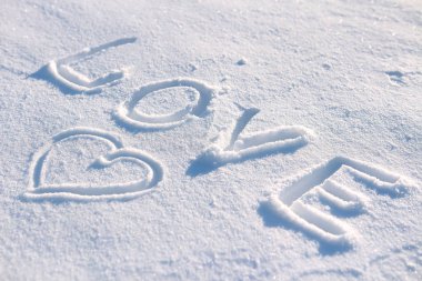 Kelime aşk ve karda çizilmiş bir kalp.