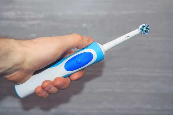 Bir elektrikli diş fırçası tutan eller.