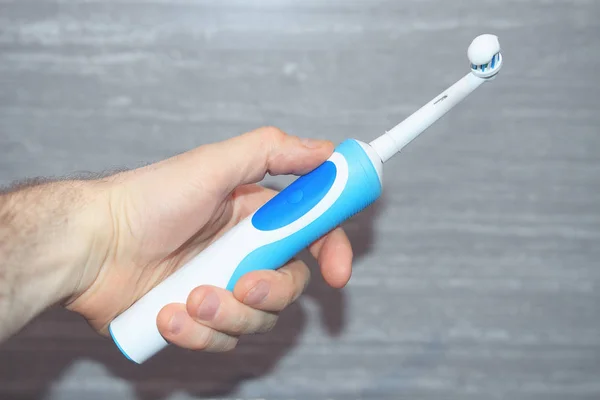 Mão humana segurando uma escova de dentes elétrica . — Fotografia de Stock