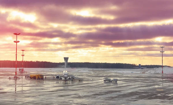 Avión en mantenimiento antes del vuelo en el aeropuerto una puesta de sol . — Foto de Stock