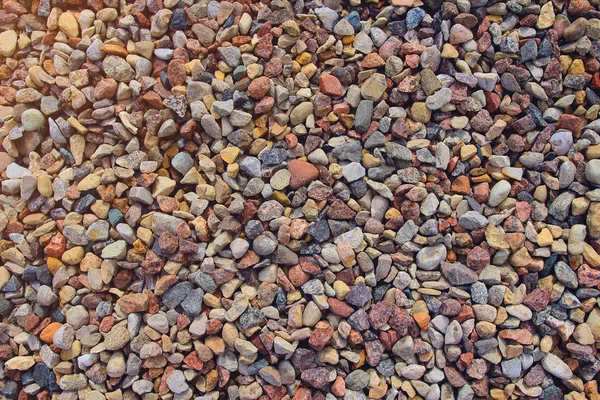 Textura y fondo de pequeños guijarros de colores en la playa . — Foto de Stock
