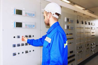 endüstriyel güç ortaklığının beyaz kask içinde mühendis Başlat düğmesini denetim masasında presler.