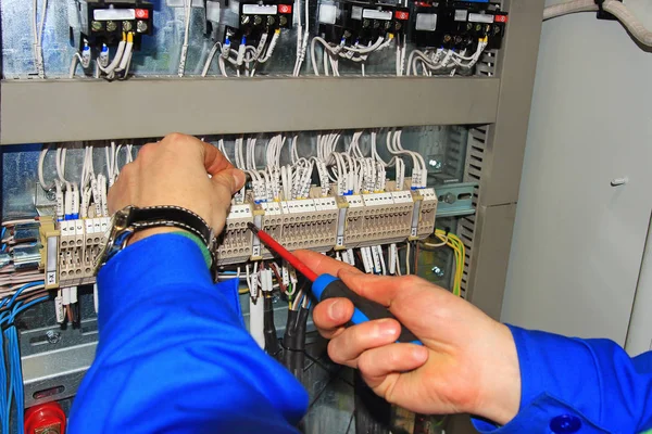 Macro electrician's hands with screwdriver connect wires on background of electrical cabinet — Stock Photo, Image