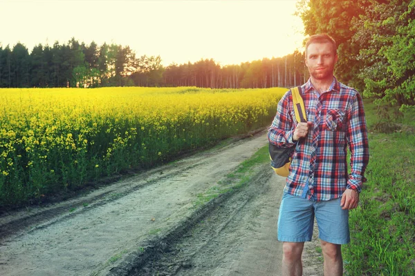 Young tourist with a backpack on road looking forward to sunset in nature