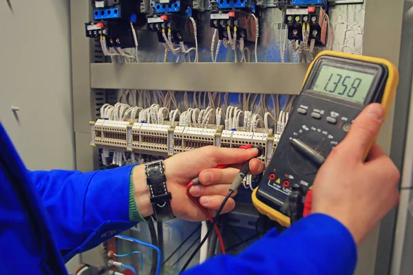 Engenheiro ajusta circuito elétrico da automação e faz multímetro uma medição — Fotografia de Stock