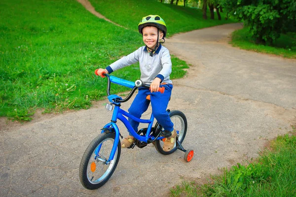 Seorang anak yang bahagia mengendarai sepeda di taman kota hijau di jalan setapak — Stok Foto