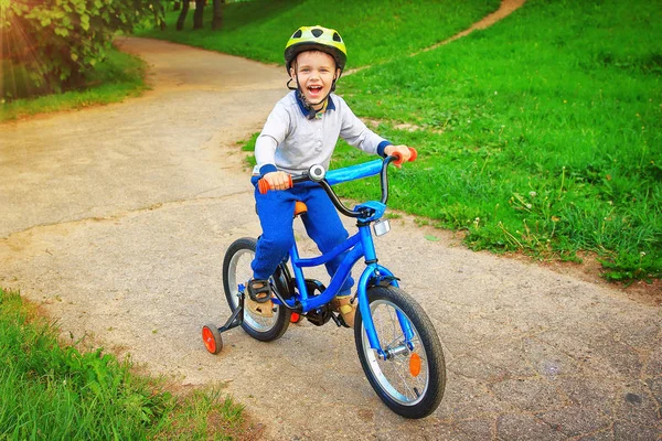 Seorang anak yang antusias dan ceria di atas sepeda di taman hijau merasa senang dan berteriak dengan penuh kegembiraan — Stok Foto