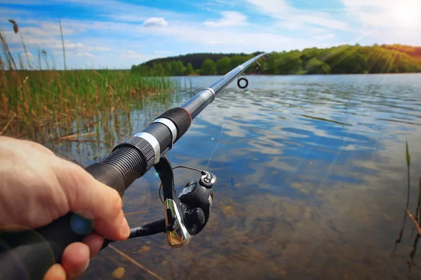 Pesca en el lago en el día soleado. Manos y caña de pescar de pescador macro —  Fotos de Stock