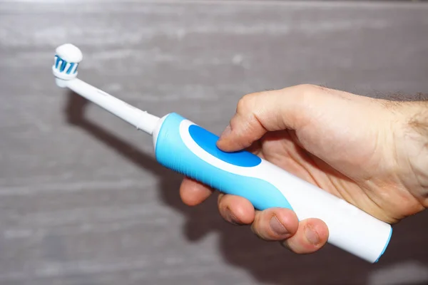 Electric toothbrush in hand personal hygiene in the bathroom