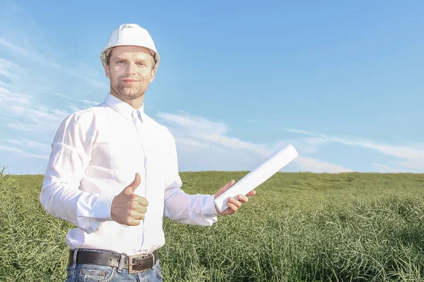 Parmağını dayanabiliyor ve gülümseyen planları ile beyaz kask içinde mimar mutlu mühendis