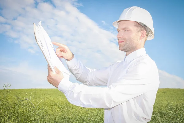 Ingenieur architect verwijst naar tekeningen van projectdocumentatie op de website van de bouw van onroerend goed. — Stockfoto