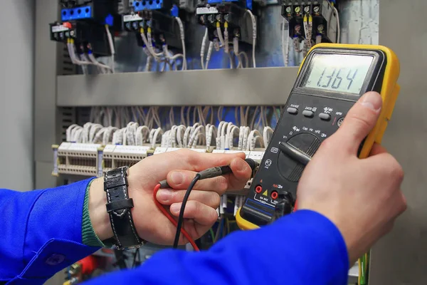 Elektrikçi elektrik kabine multimetre ile gerilim ölçer.