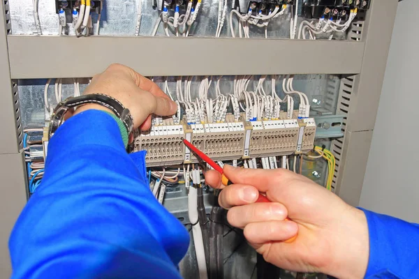 Engenheiro prende fios elétricos em terminais de armário elétrico com chave de fenda . — Fotografia de Stock