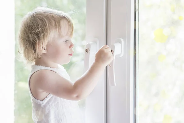 Dítě otevře okno. Malá holčička na okno. — Stock fotografie