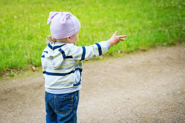 Niño en el camino mira y muestra su mano hacia adelante — Foto de Stock