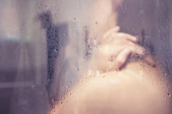 Girl in shower behind glass with drops — Stock Photo, Image