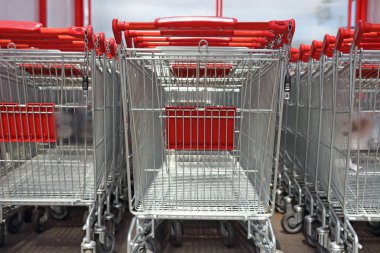 alışveriş arabaları ile Kırmızı saplı satırda ayakta. Alışveriş kavramı.