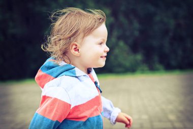 Sarı bukleler ile çocuk yeşil park arka plan üzerinde çalışıyor. bir yaz gününde etkin alt close-up. Sağlıklı yaşam, egzersiz, gençlik spor, çocuk portresi