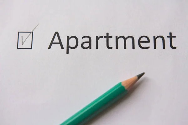 To buy an apartment. word APARTMENT is written on white paper with tick and  gray pencil.