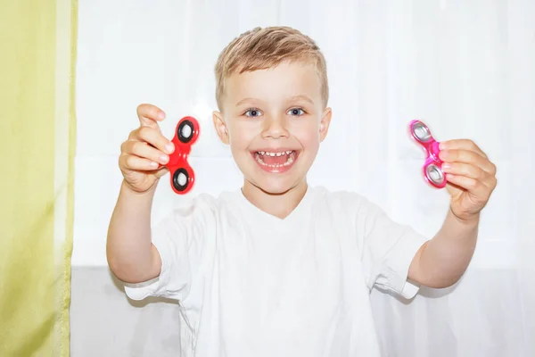 Happy young boy holding two fidget spinners. — Stock Photo, Image