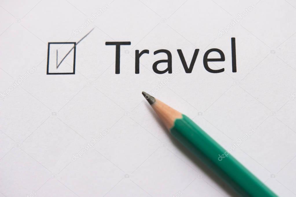 To travel. To make dream come true. word TRAVEL is written on white paper in pencil marked with  tick