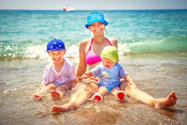 Feliz familia bañándose en el mar. Madre sonriente con su hijo y su hija en la playa. Vacaciones de verano en la playa . — Foto de Stock