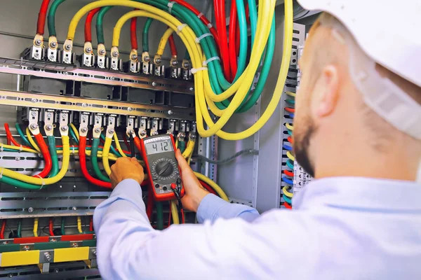 Engenheiro eletricista mede tensão com multímetro em gabinete de alta tensão — Fotografia de Stock